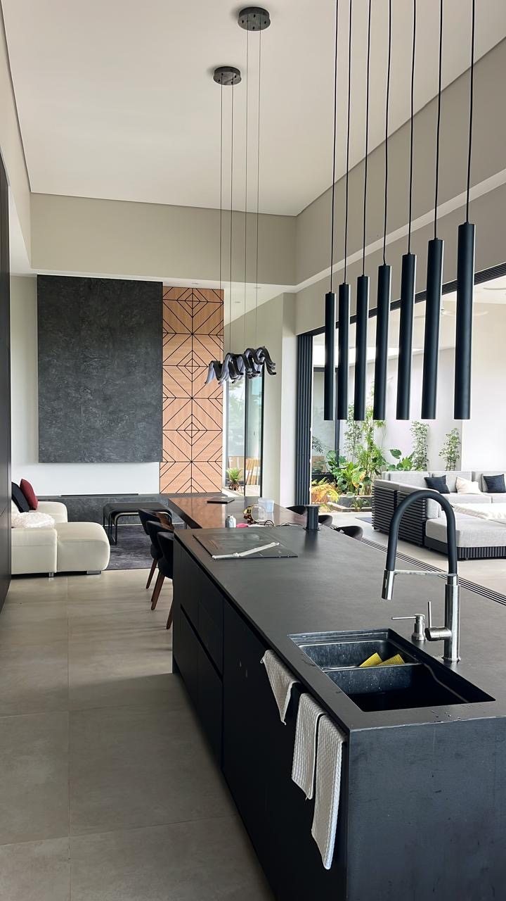 Living room with cream leather sofa, black kitchen island and seven pendant lights
