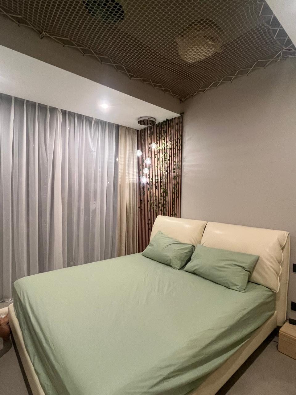 Green bedroom with oak slat headboard, glass pendants and a rope net ceiling